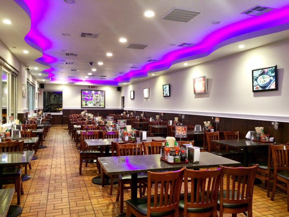 Dining room with long tables under purple ceiling lights