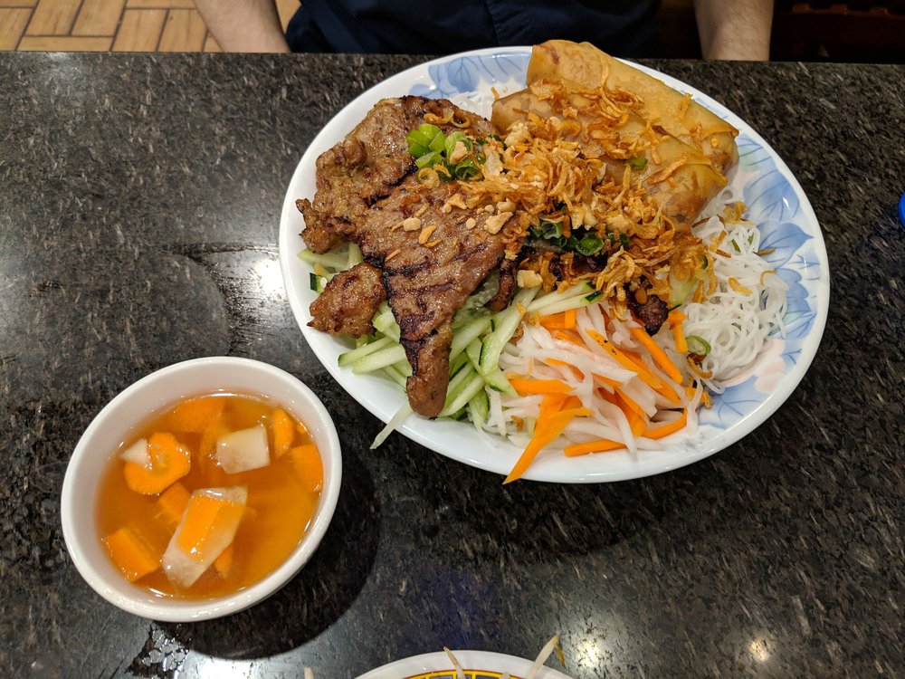 Grilled beef and a fried egg roll over vermicelli with pickled vegetables